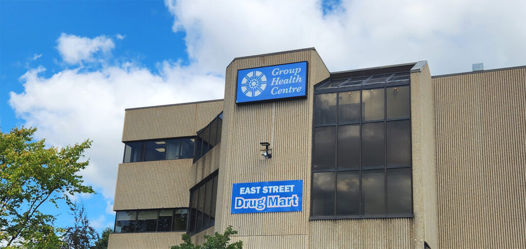 A blue Group Health Centre sign at the top of a building