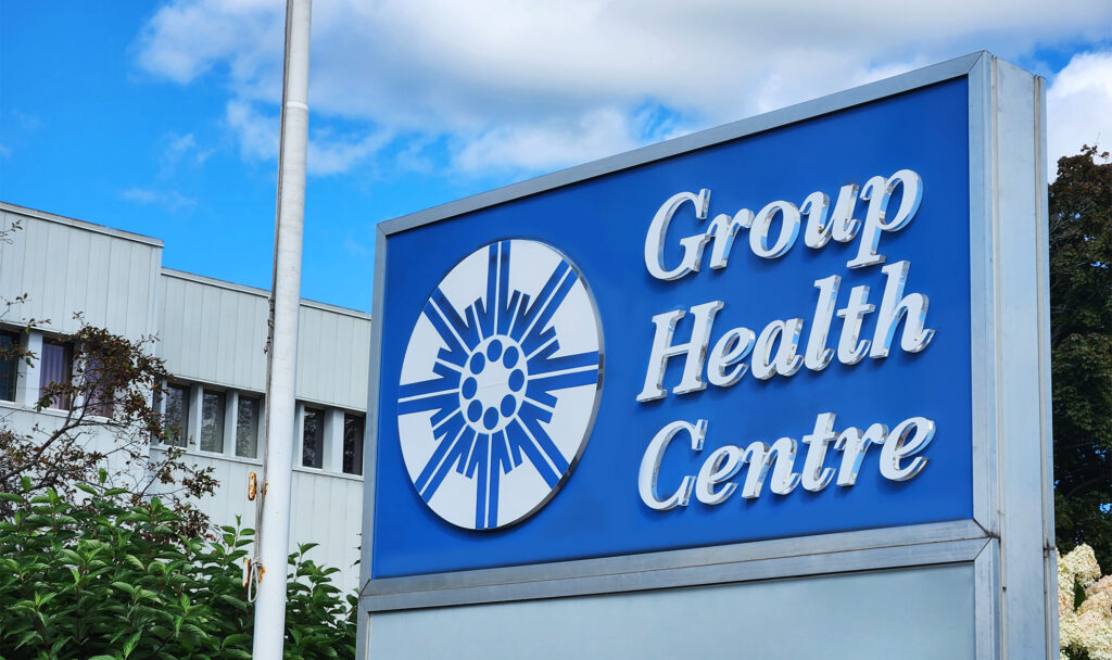 A close up of the blue Group Health Centre sign in front of their building.